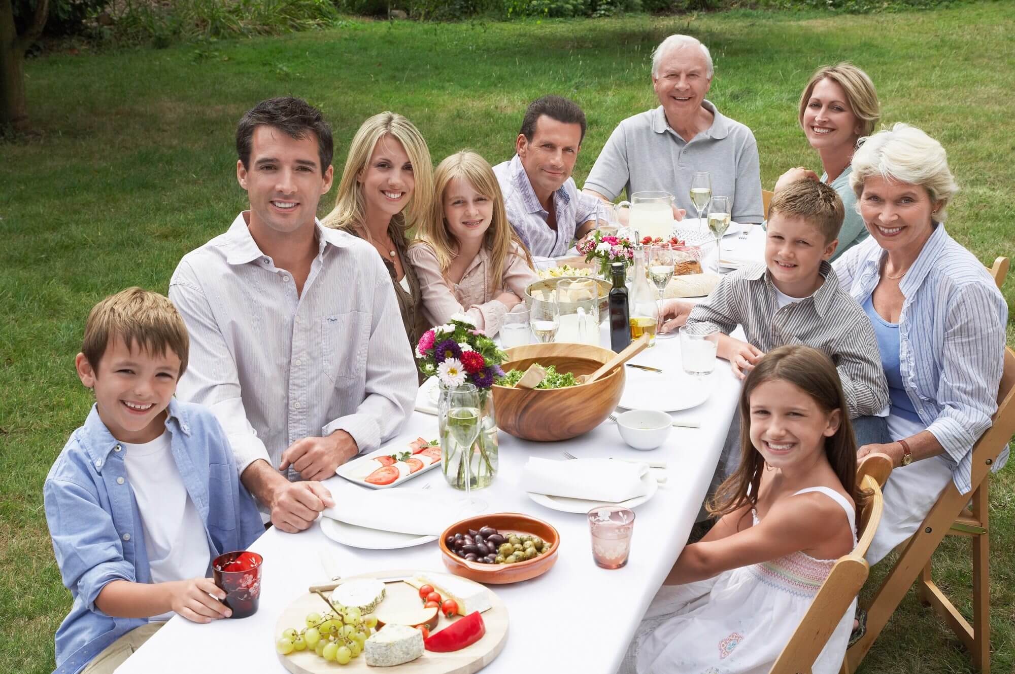 multigenerational family eating dinner around a table outside